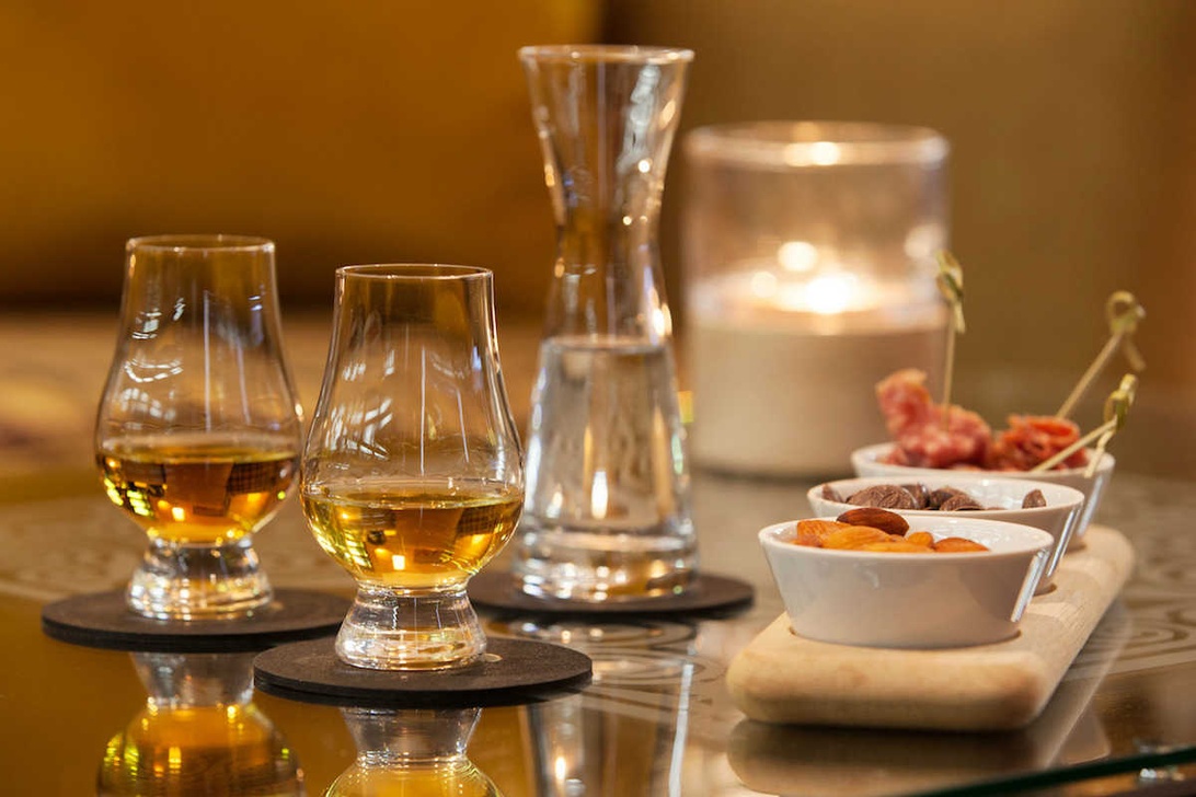 Elegantes Whisky-Tasting-Setup mit Gläsern, Karaffe und Snacks